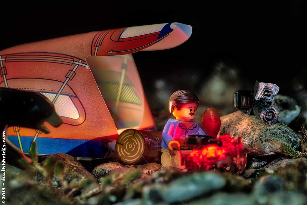 Lego man eating chicken in front of a tent at night, when suddenly a bear shows up.